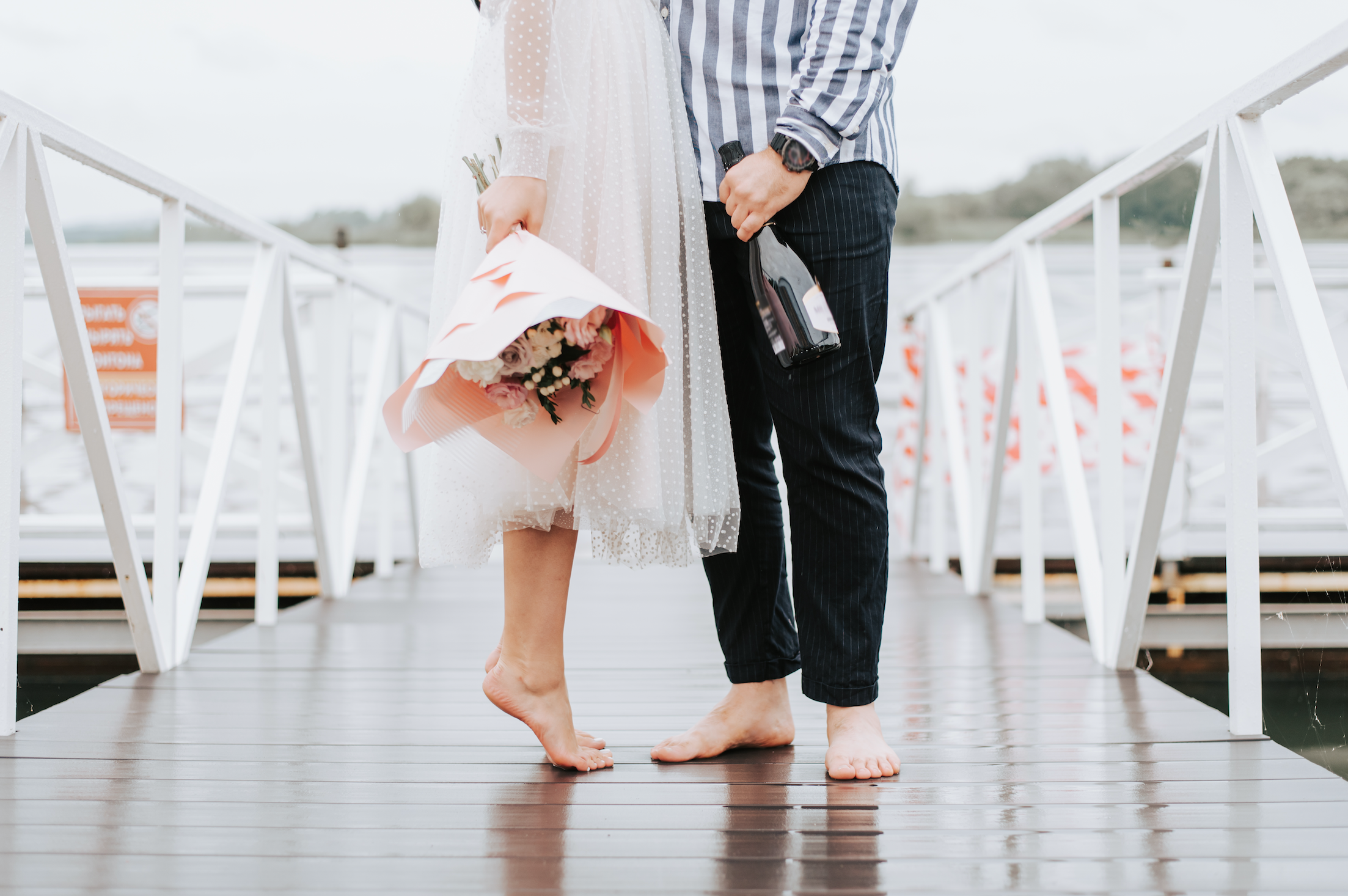 Feet of the newlyweds on the pier. Legs of the bride and...